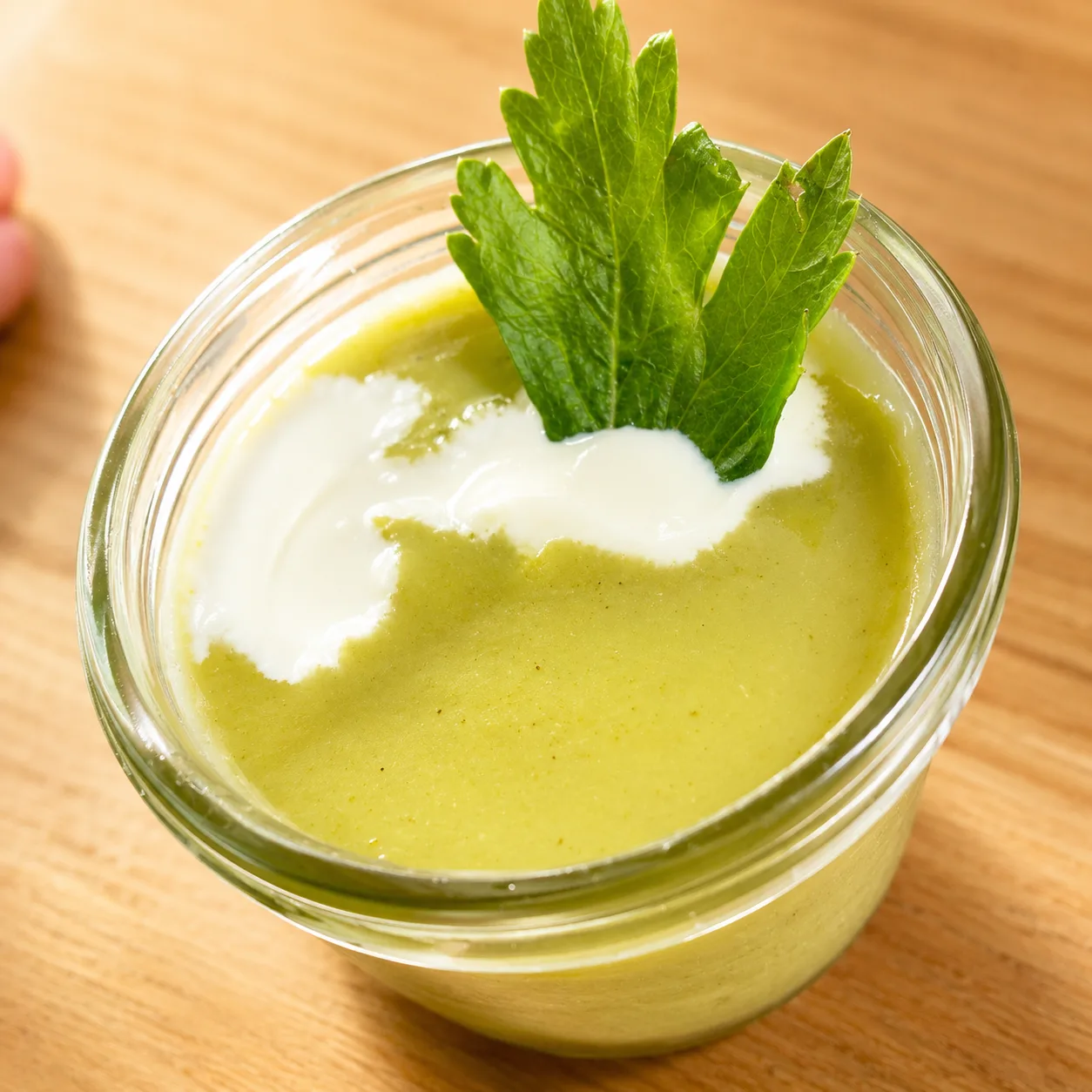 Soupe de courgette servie dans un petit bocal avec une feuille fraîche.